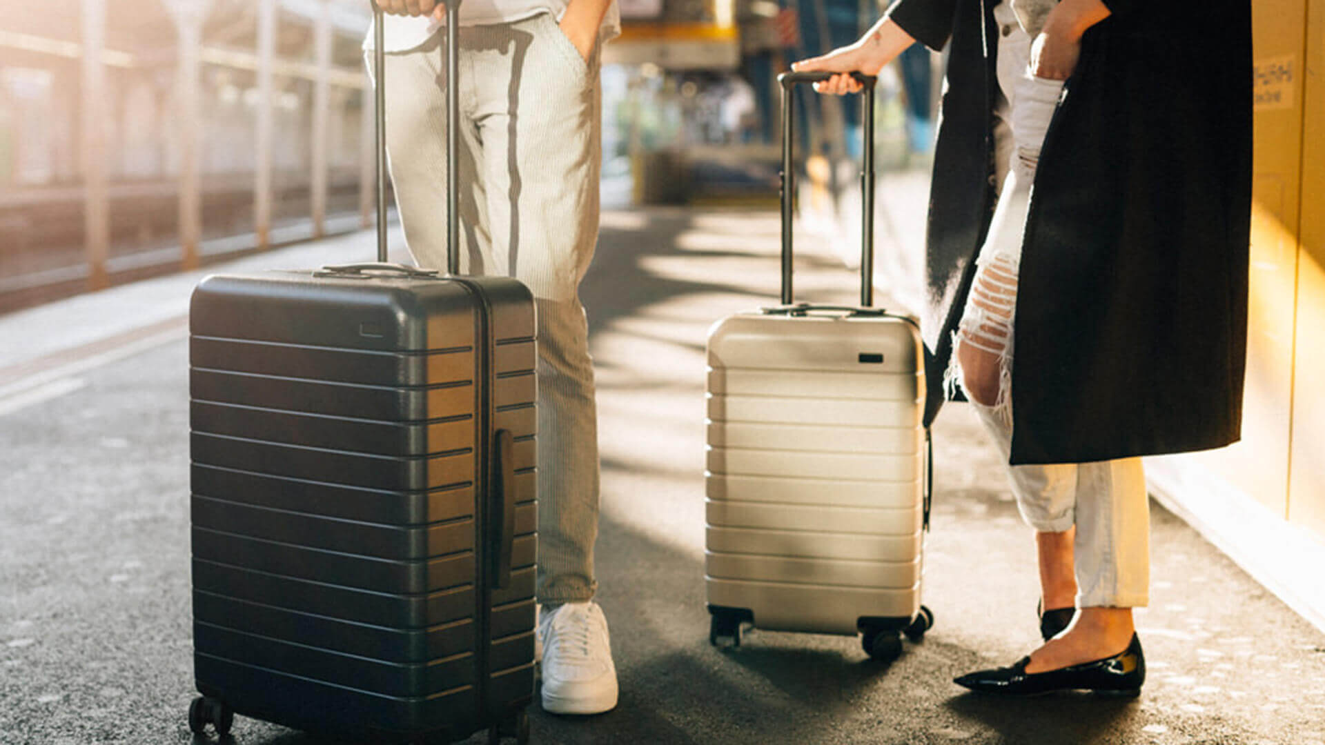 Two people standing next to each other with travel trolleys.